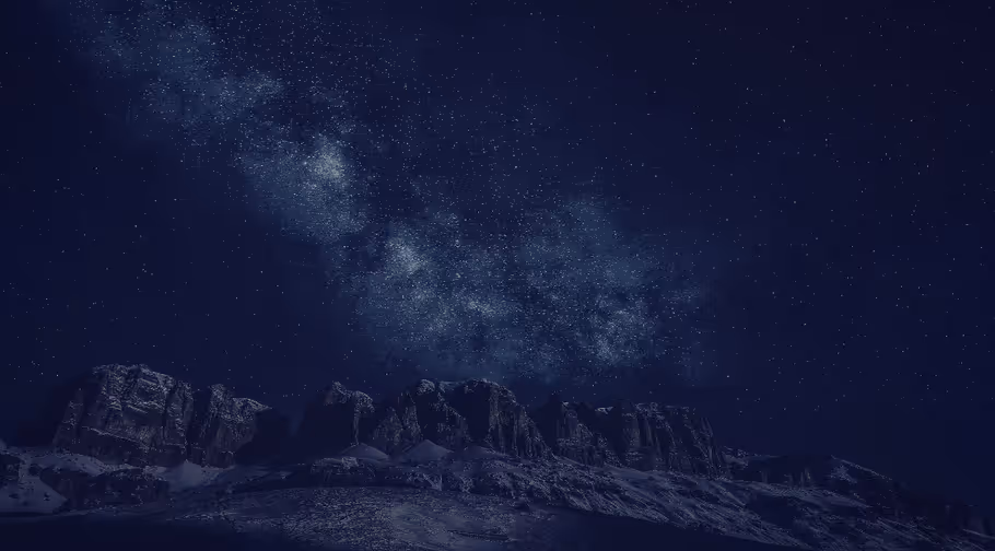 Ciel nocturne étoilé au-dessus de montagnes sombres.