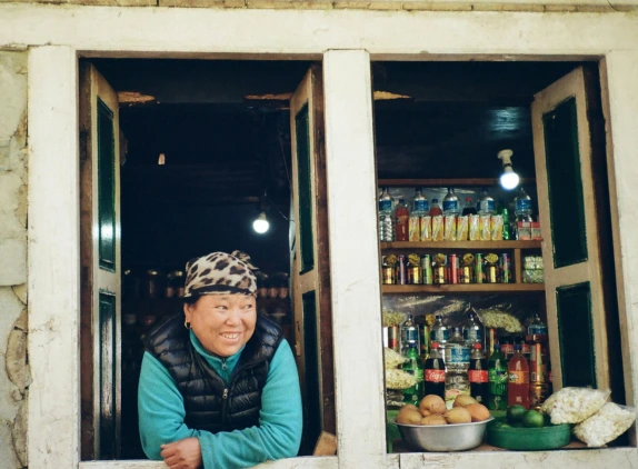Femme népalaise souriante devant sa boutique.