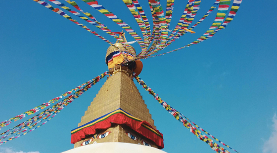 Grand stupa blanc avec drapeaux de prières au vent.