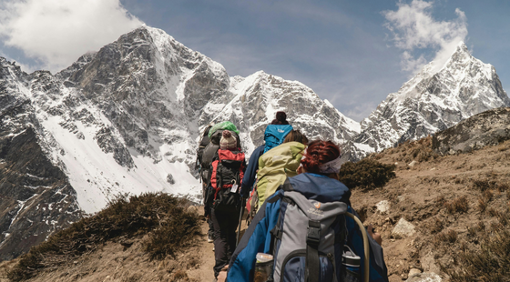 Randonneurs avançant sur un sentier face aux montagnes enneigées.