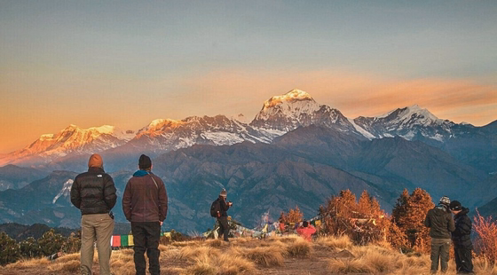 Trekkeurs au lever du soleil face aux montagnes himalayennes.