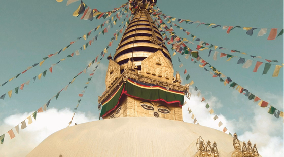 Grand stupa blanc orné de drapeaux de prières.