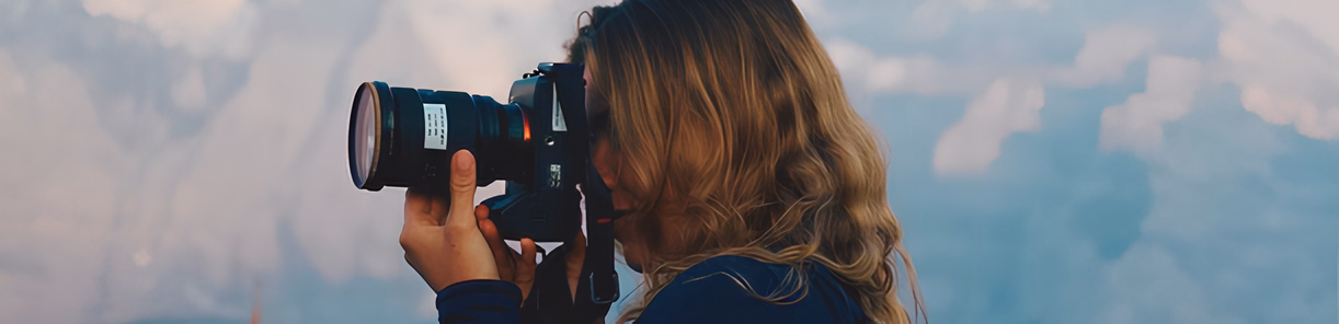 Femme photographe tenant un appareil photo dans la nature.