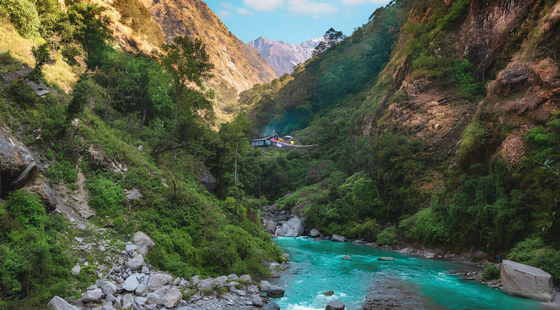 Rivière turquoise serpentant entre les falaises verdoyantes d’une vallée népalaise.