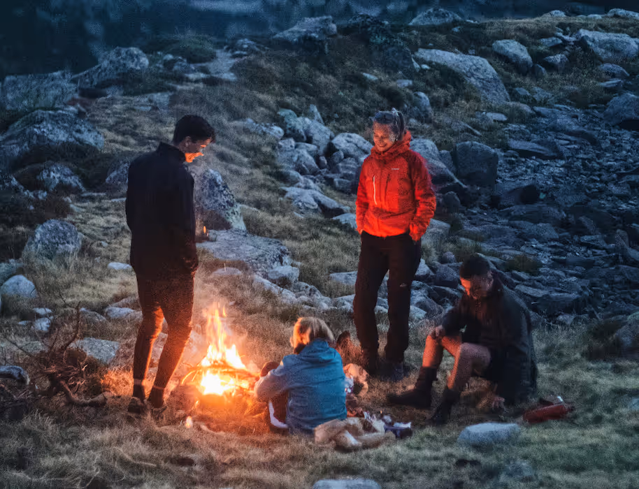 Randonneurs réunis autour d'un feu de bivouac en montagne