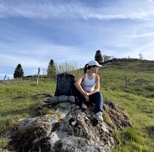 Agathe Bildstein assise sur un rocher en altitude, paysage de landes et ciel bleu, co-créatrice trek Vosges en Hamac