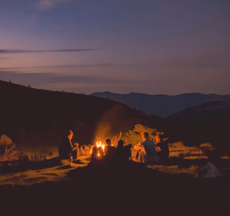 Bivouac en groupe autour d'un feu de camp à la nuit tombée en montagne, trek Vosges en Hamac