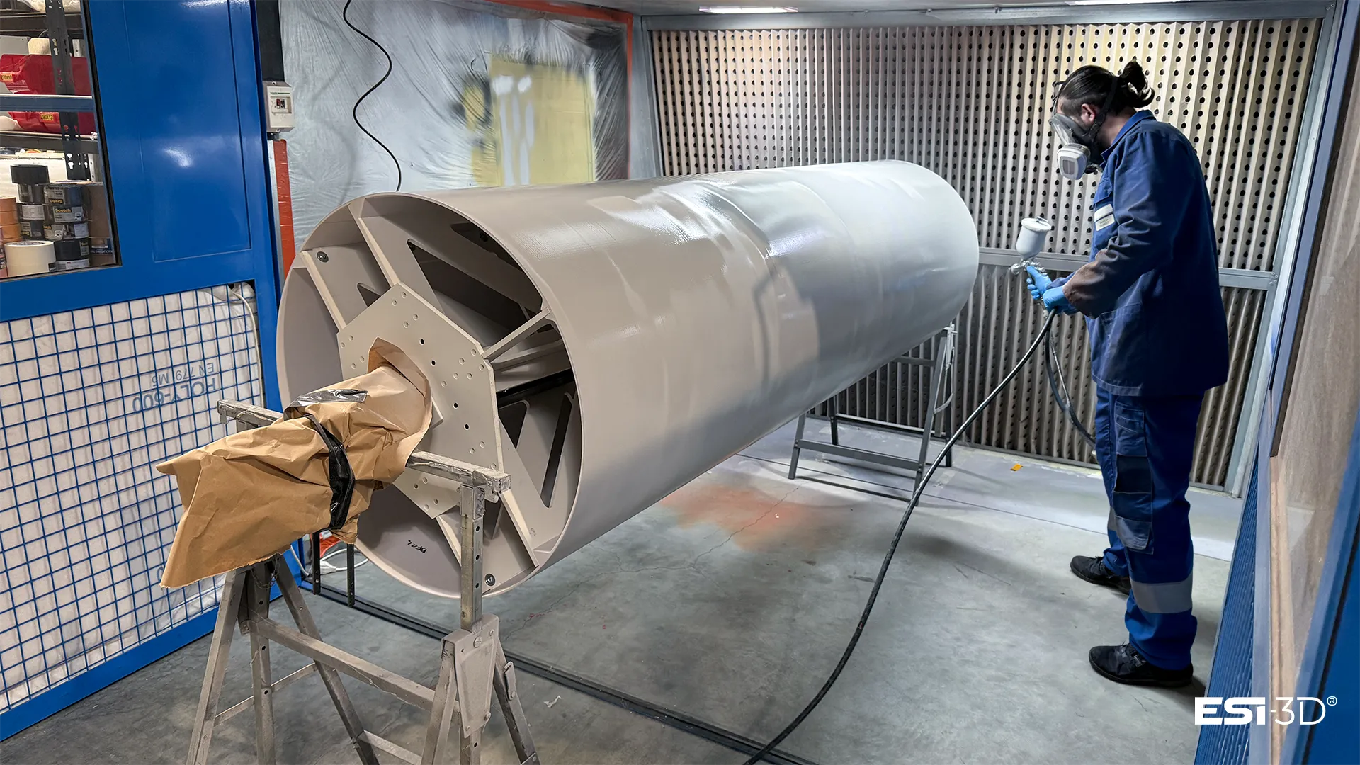 Mise en peinture au pistolet d'une section du fuselage de la maquette Ariane 6 en cabine de peinture