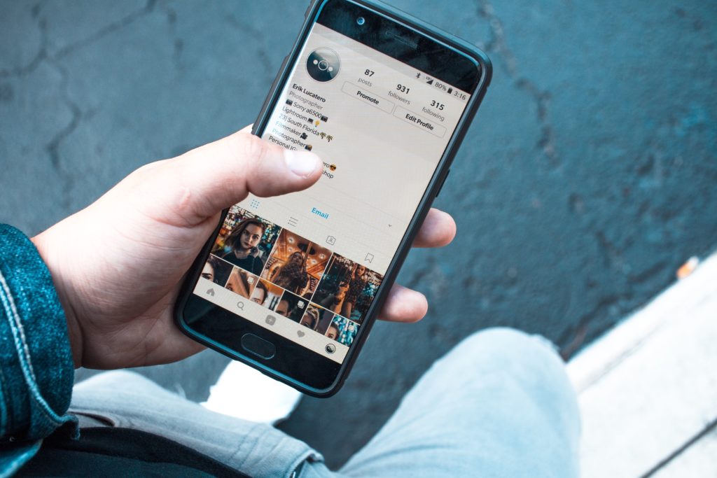 一人手持智慧型手機，螢幕顯示 Instagram 個人檔案。
