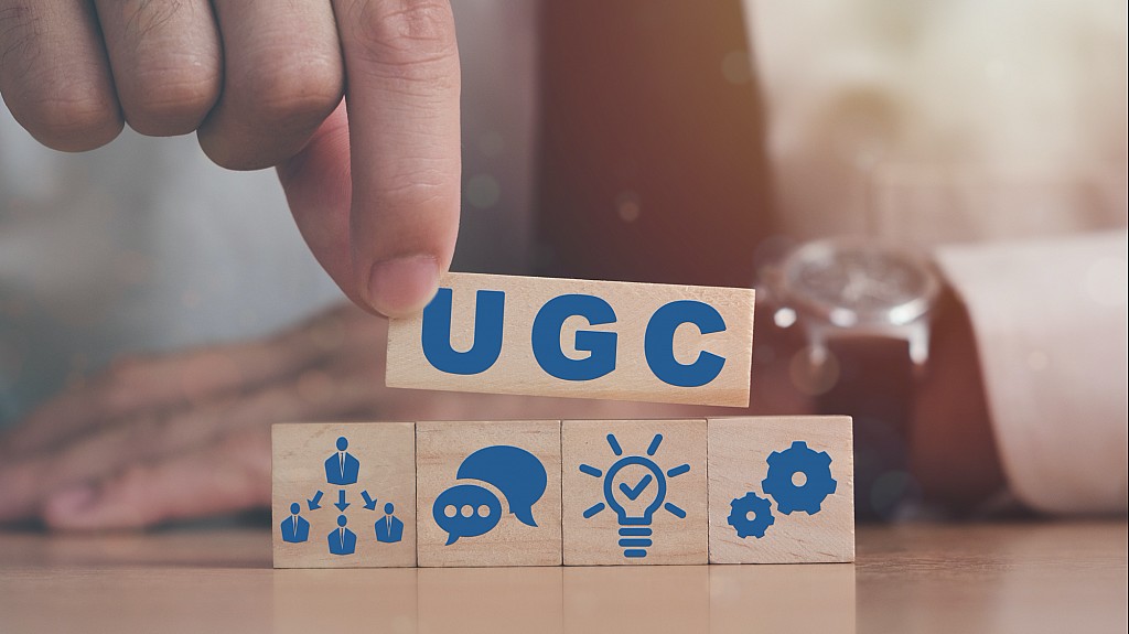 手放置刻有「UGC」的木塊，旁邊配有創意與團隊合作的圖示。