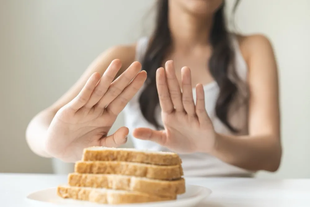 Person feeling full after a few bites with untouched plate of food showing early satiety symptoms