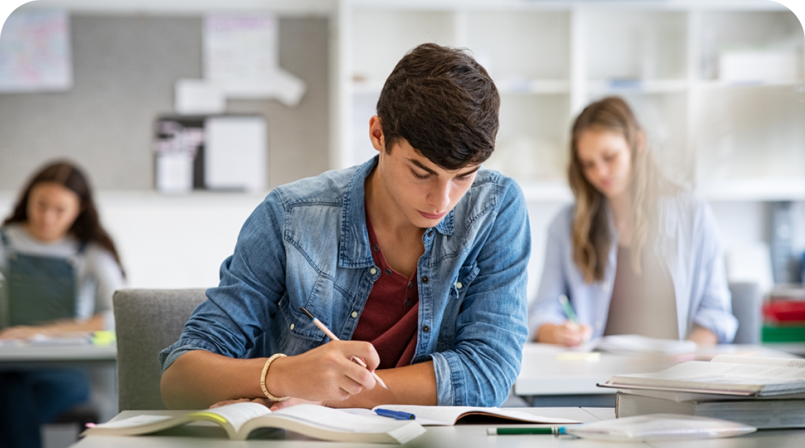 Aluno de 18 anos concentrado em anotações com livros sobre a mesa