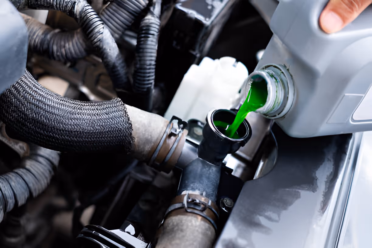 Green coolant being poured into car engine through funnel