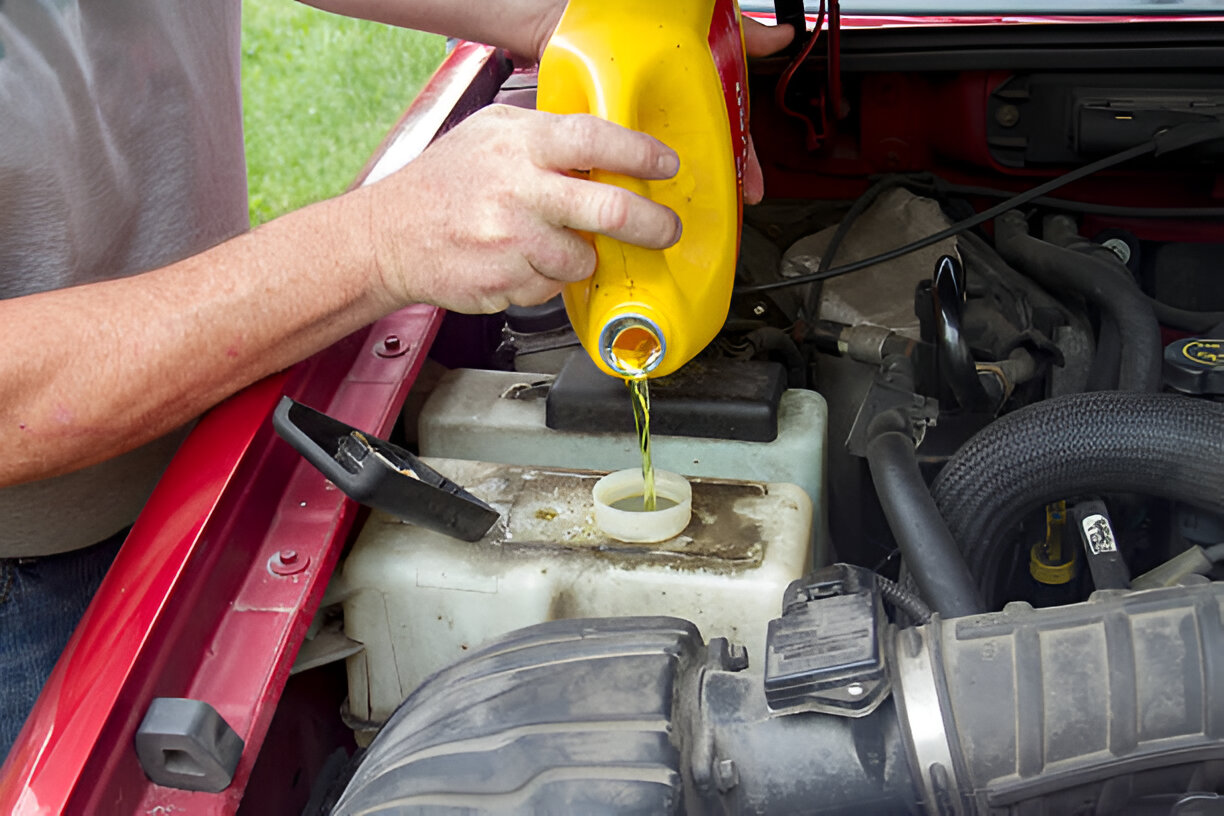 Pouring yellow motor oil into car engine from plastic container