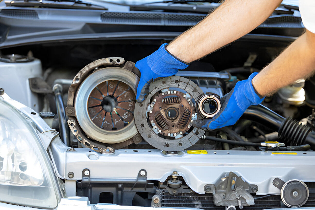 Mechanic repairing car clutch with blue gloves in engine compartment