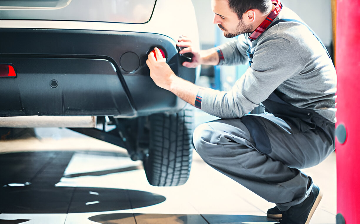 Mechanic fixing car bumper in auto repair shop workshop