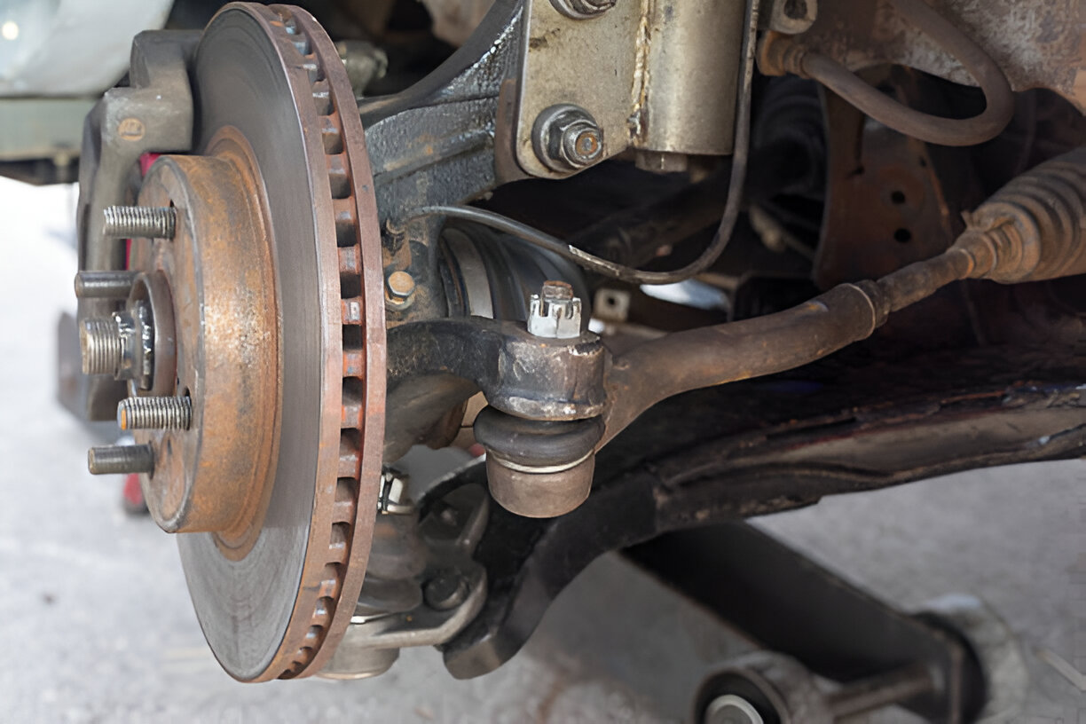 Rusty car brake rotor and suspension components close-up
