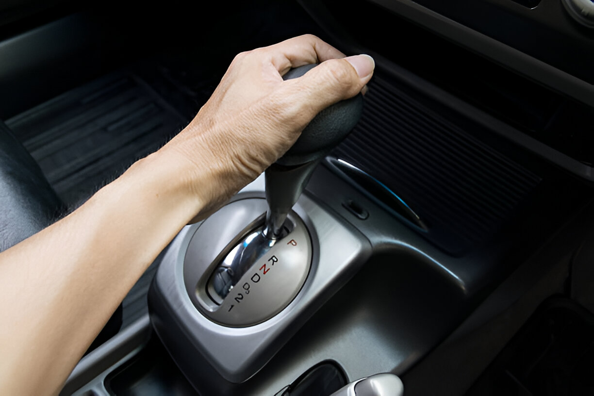 Hand shifting automatic transmission gear in car interior