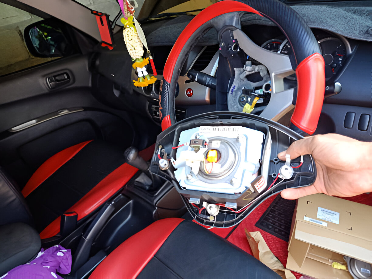 Disassembled steering wheel with exposed internal components in red and black car
