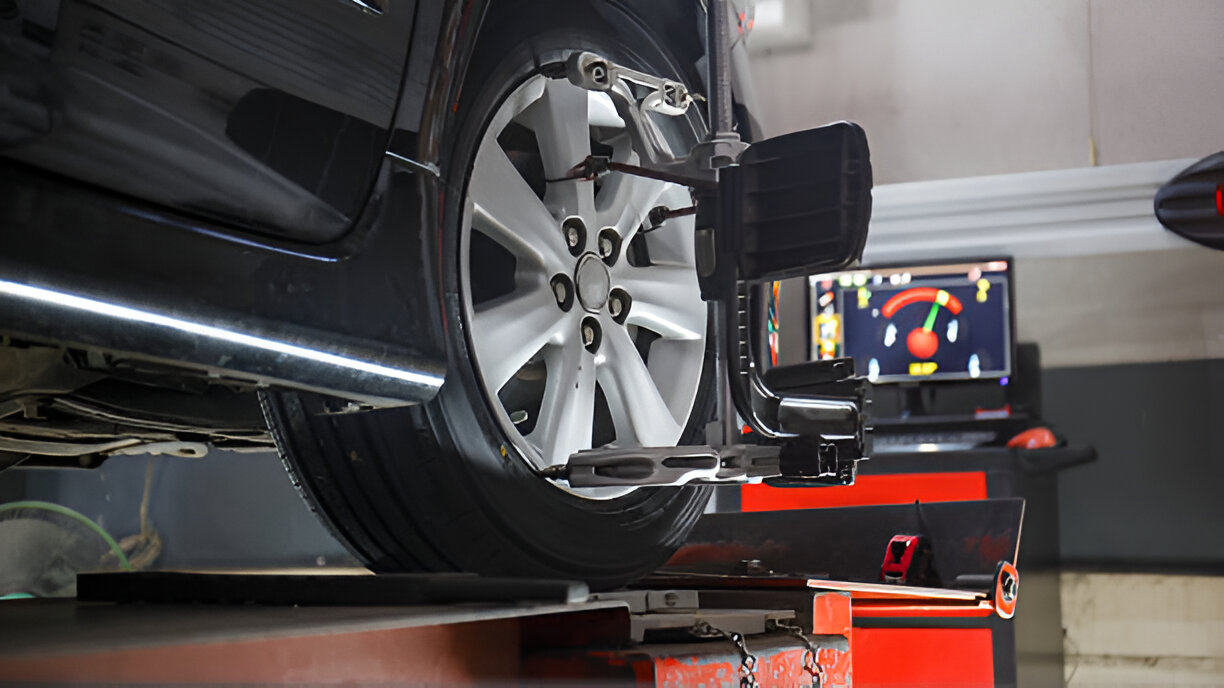 Car wheel aligned on machine with diagnostic screen in automotive service center
