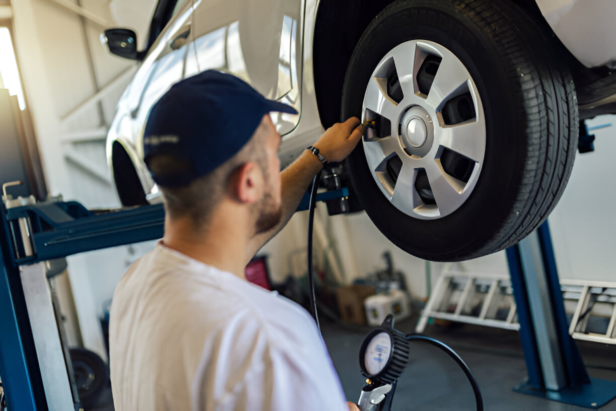 Mechanic checking tire pressure with gauge in automotive repair shop