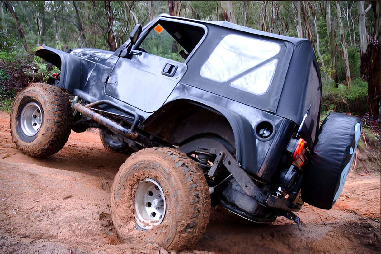 Off-road Jeep tilted at extreme angle on muddy forest trail
