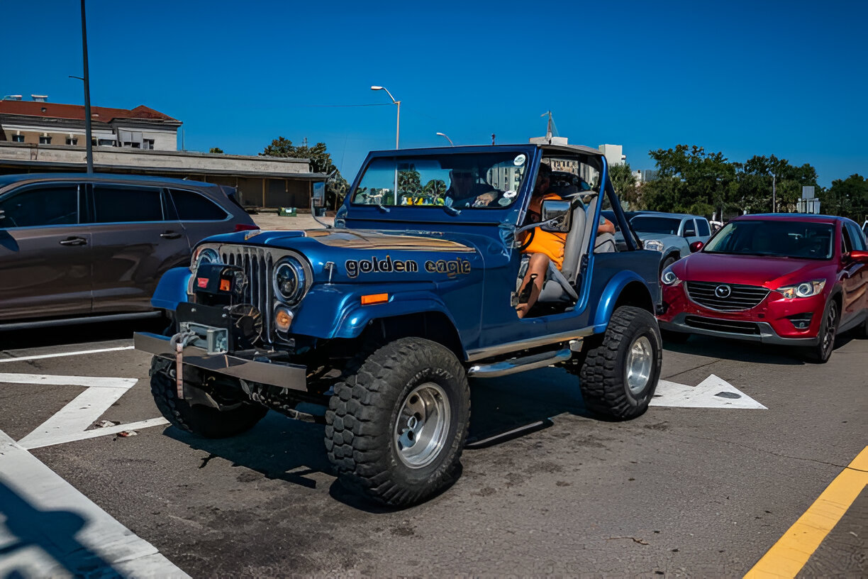 Blue vintage Jeep CJ with large tires parked in a parking lot