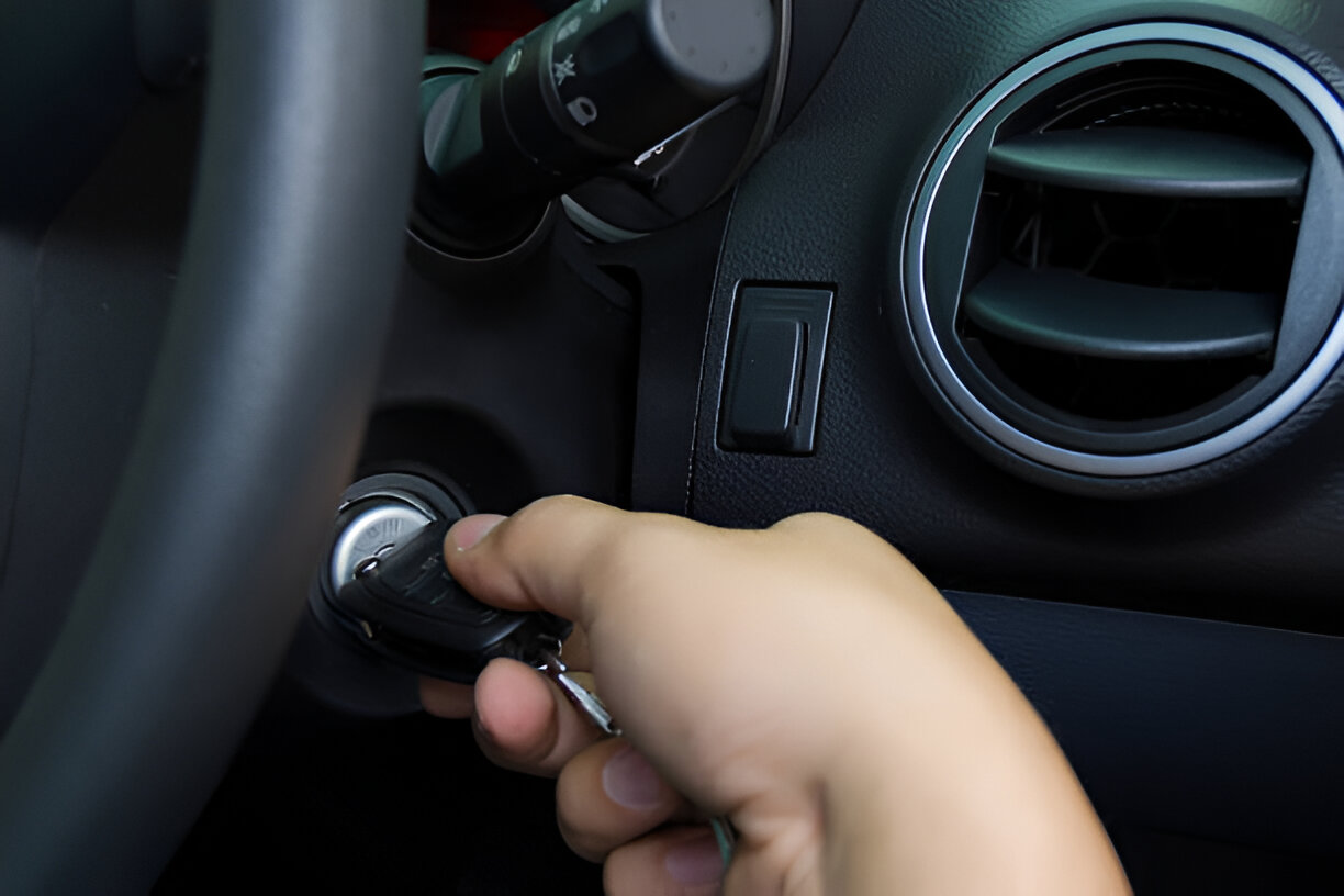 Hand inserting car key into ignition switch on vehicle dashboard
