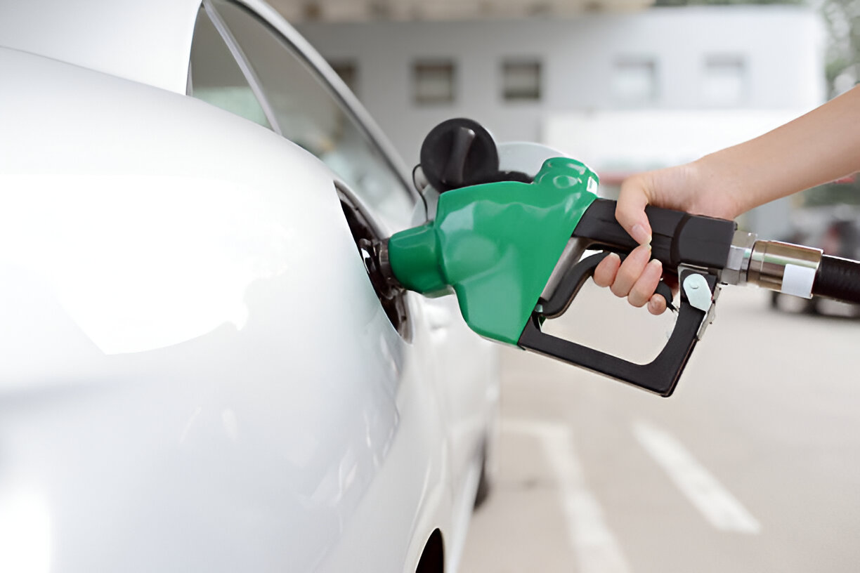 Green fuel nozzle pumping gas into white car at station