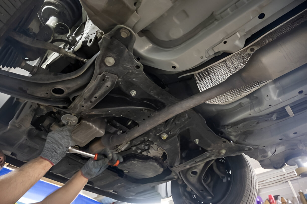 Mechanic working on car's undercarriage with hand and wrench