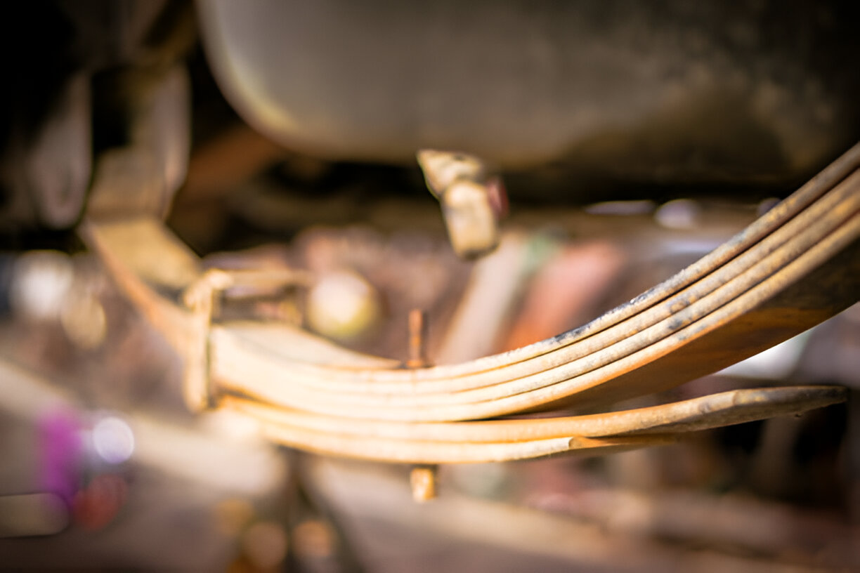 Closeup of curved wooden leaf spring suspension on vintage vehicle
