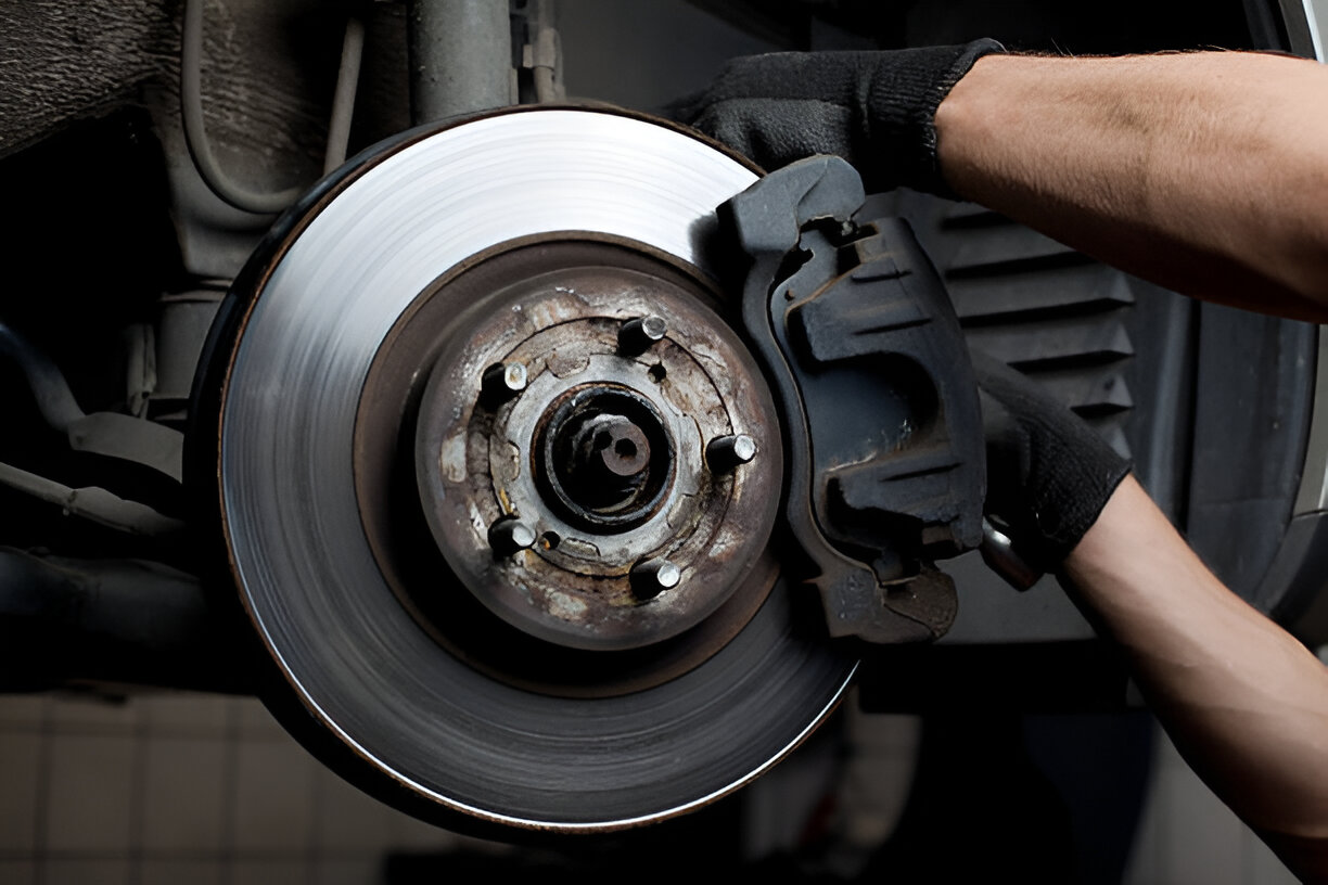 Mechanic working on car brake disc and caliper in auto repair shop