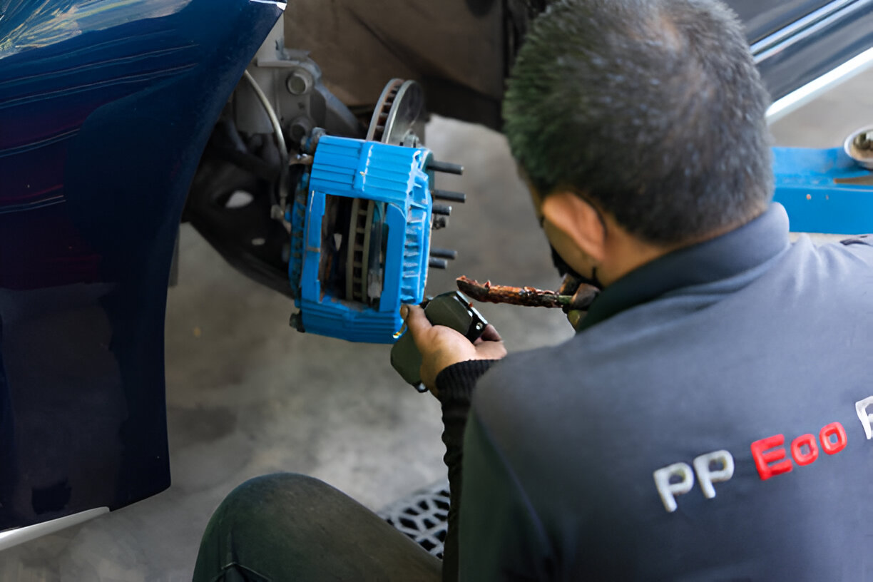 Mechanic working on car brake system with blue caliper