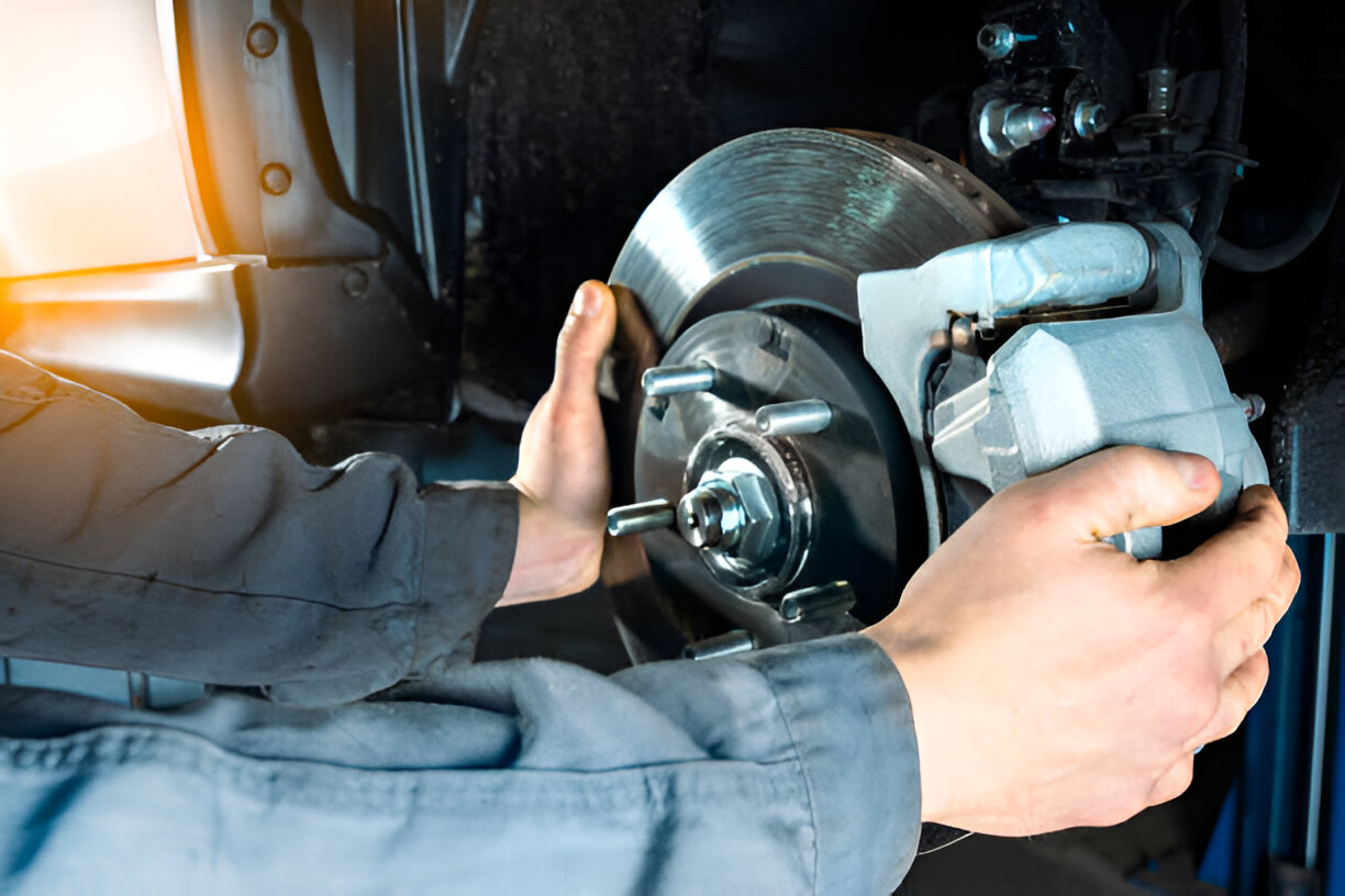 Mechanic repairing car brake disc with power tool in auto workshop