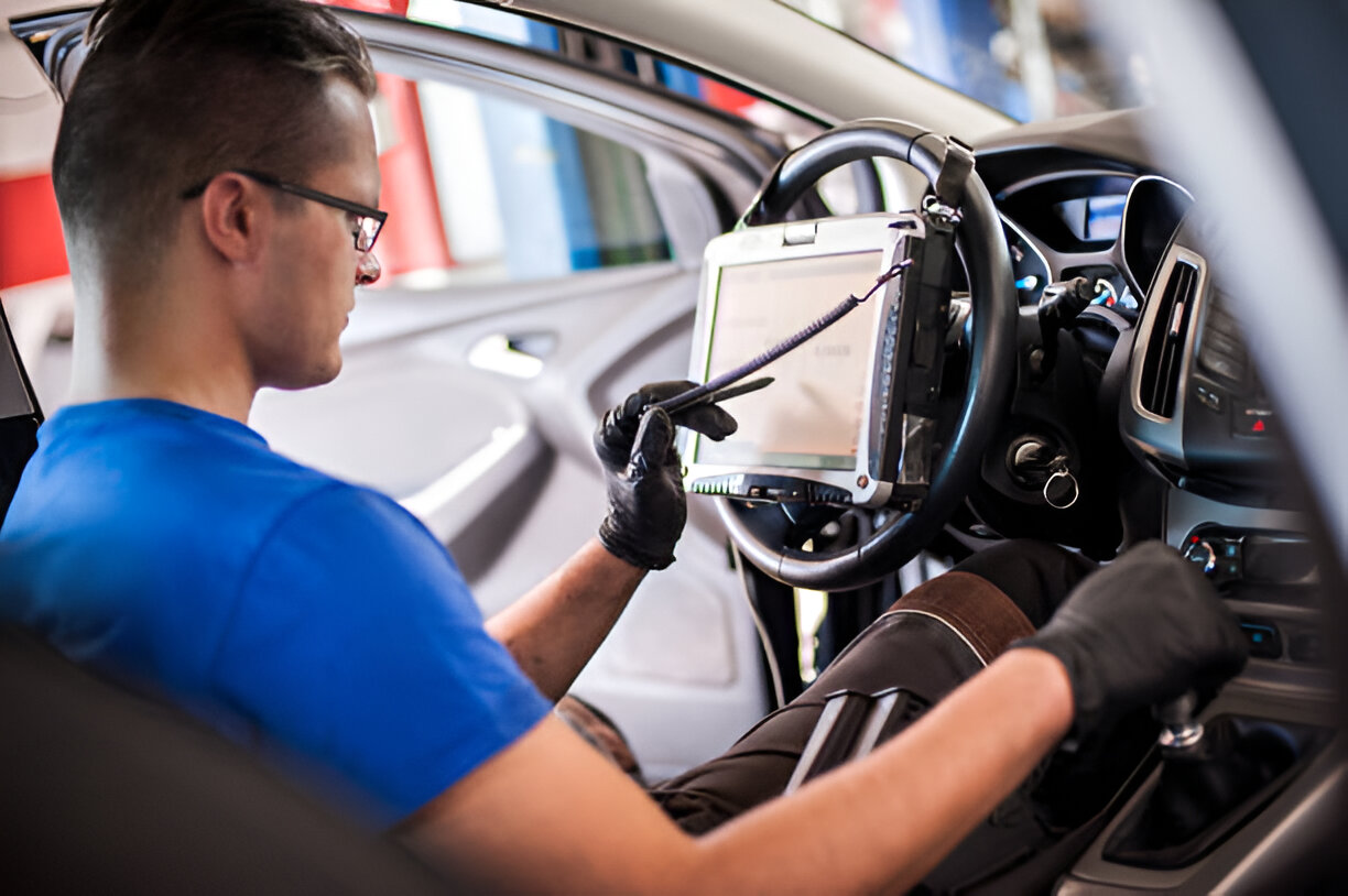 Automotive technician diagnosing car with diagnostic computer in workshop