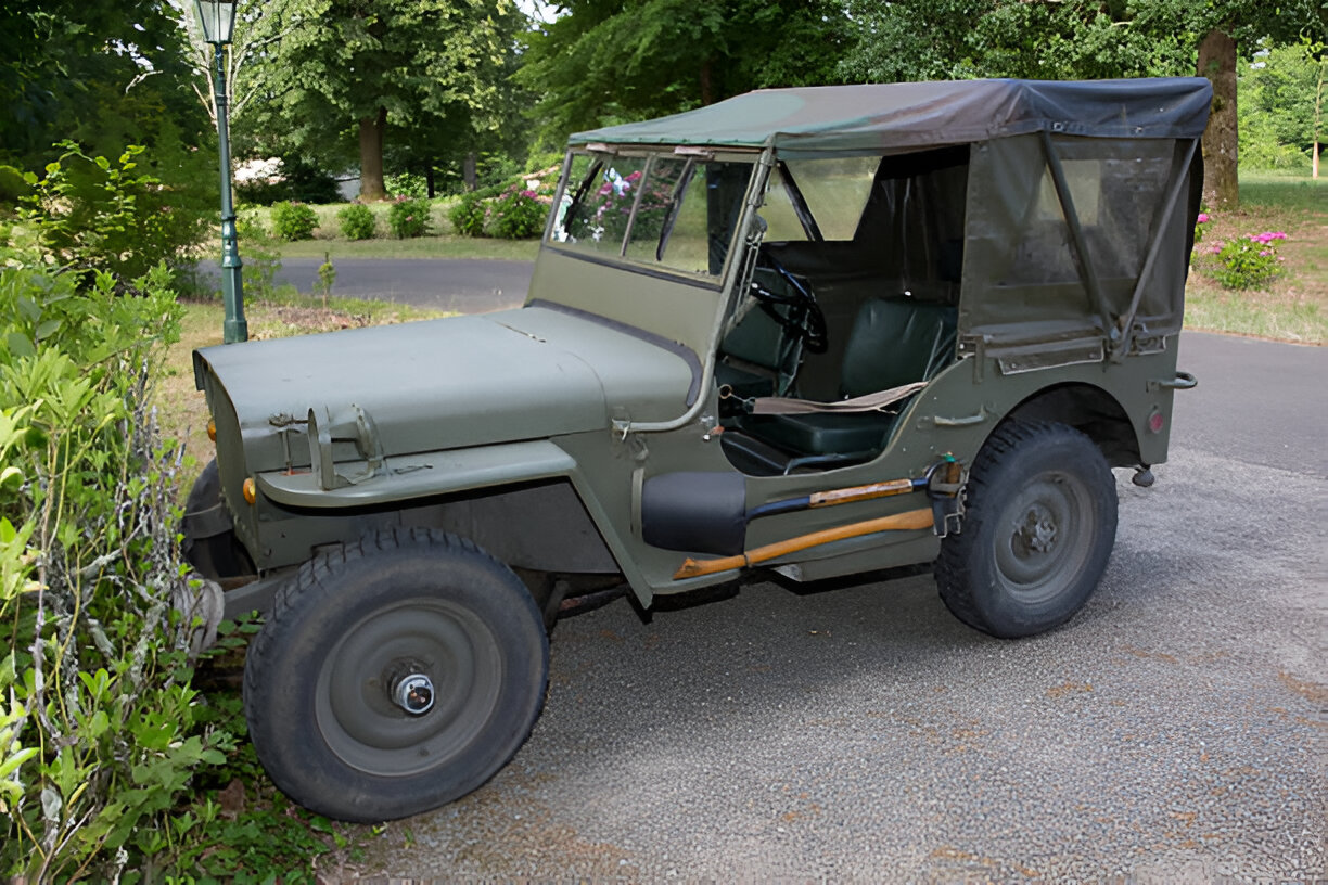 Vintage military Jeep with canvas top parked on tree-lined road