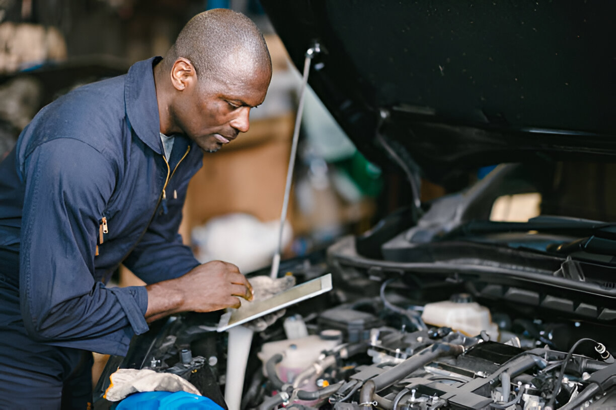 Mechanic in blue uniform checking and repairing car engine