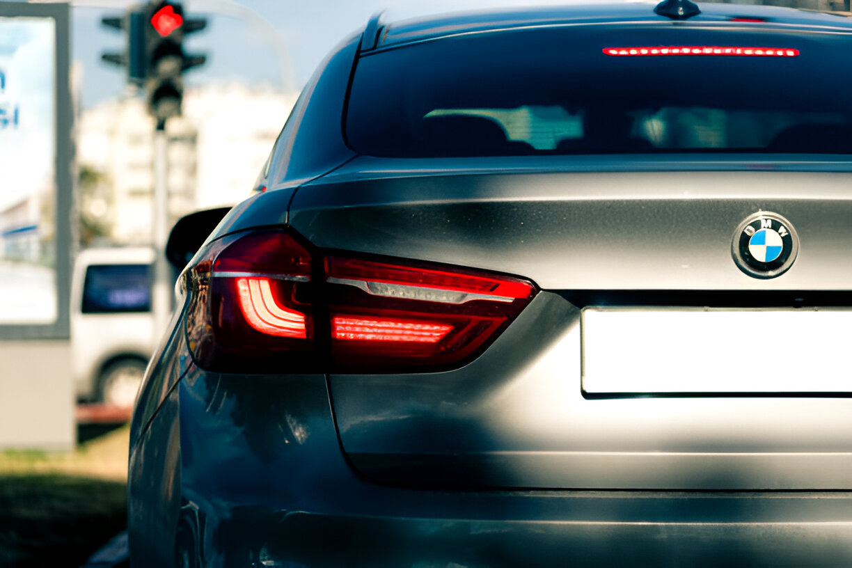 BMW car with red brake lights at an intersection with traffic light