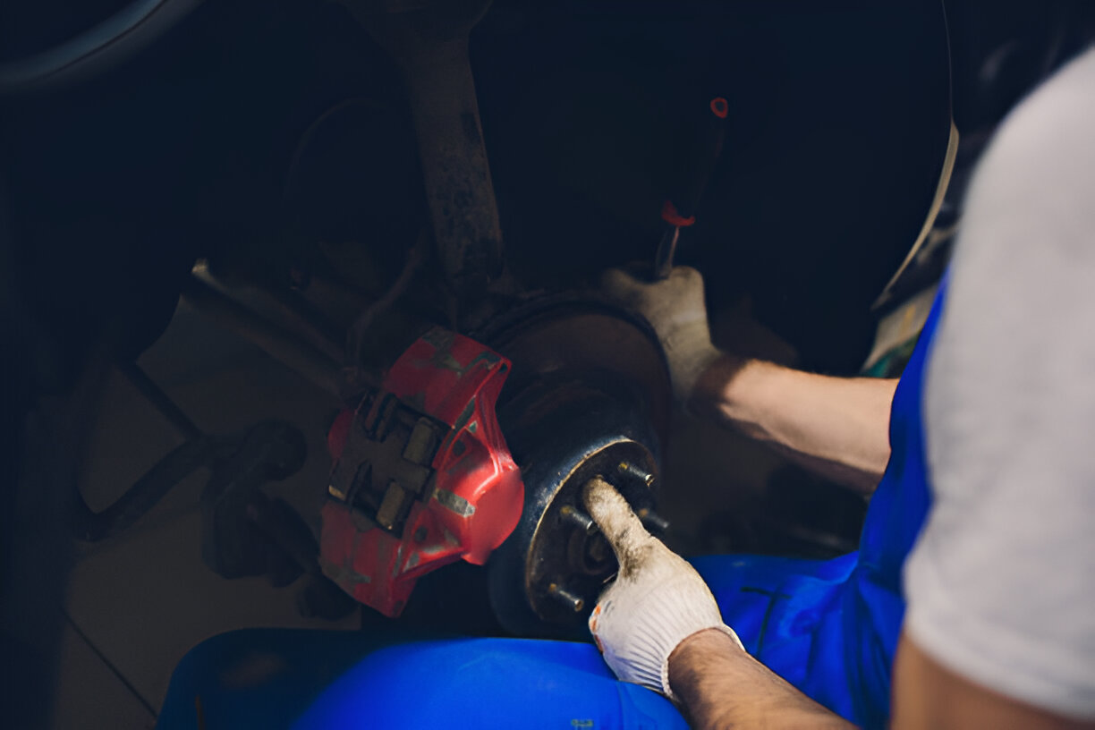 Mechanic working on car brake with red caliper and gloved hands