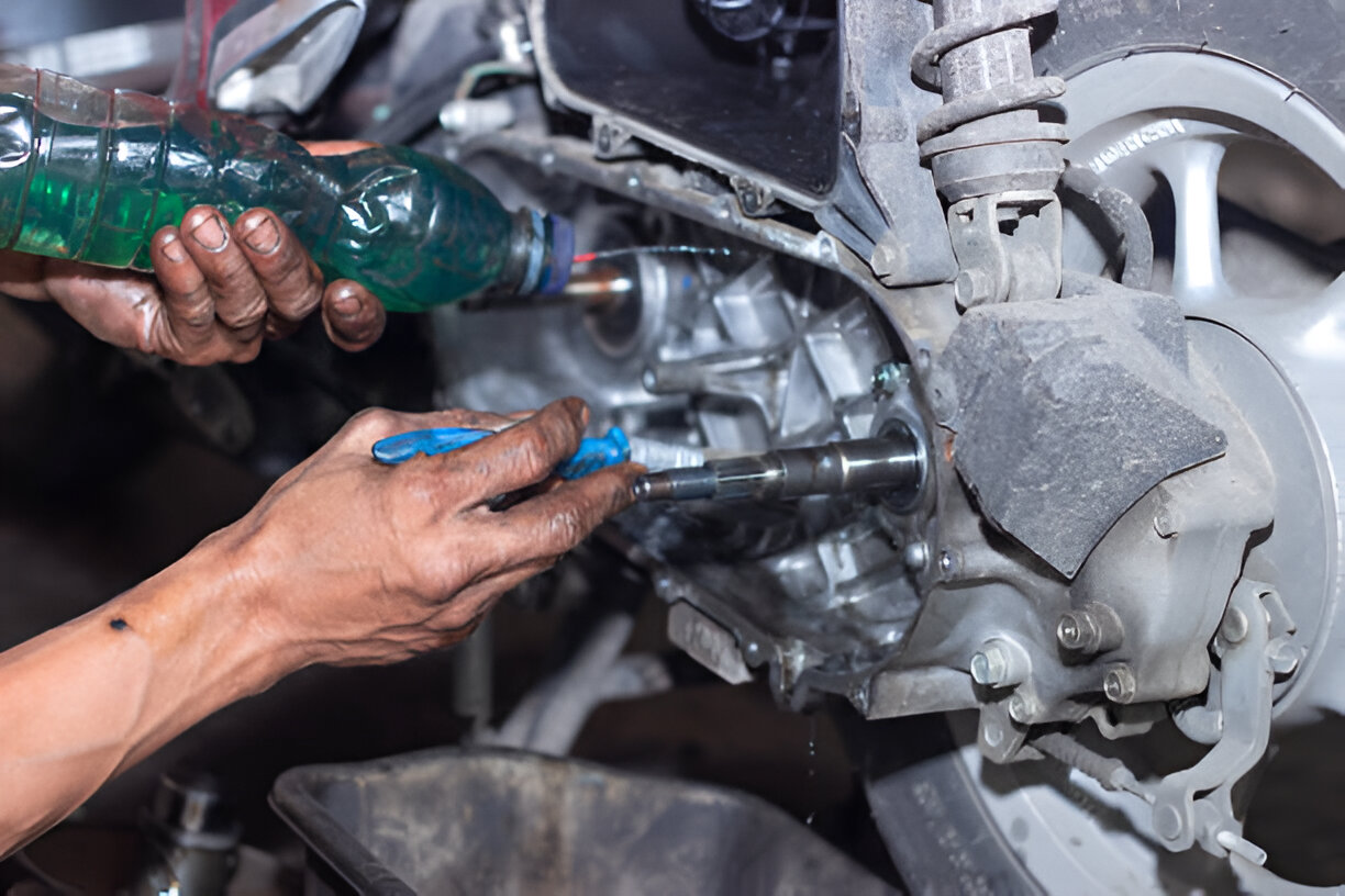 Mechanic using blue tool and green liquid while repairing car suspension