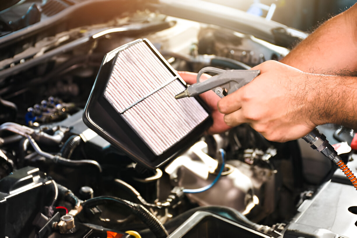 Mechanic's hand removing air filter from car engine compartment