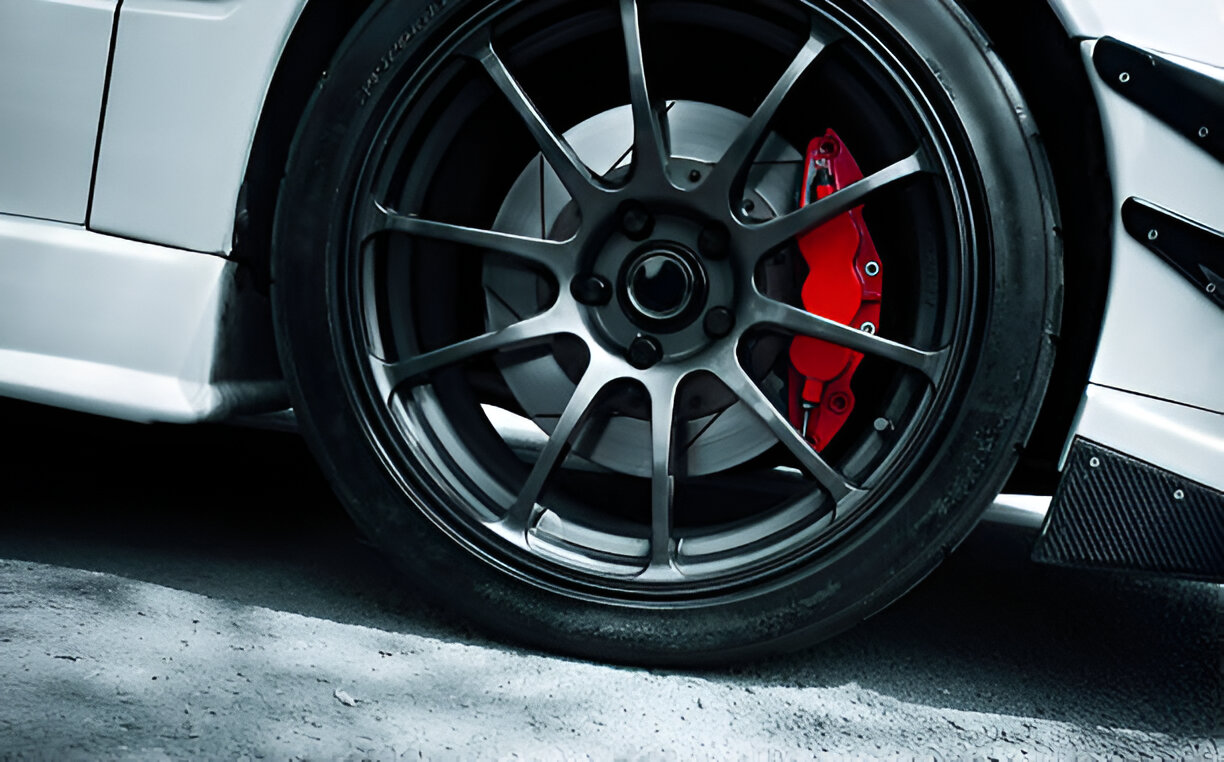 Sports car wheel with black alloy rim and red brake caliper