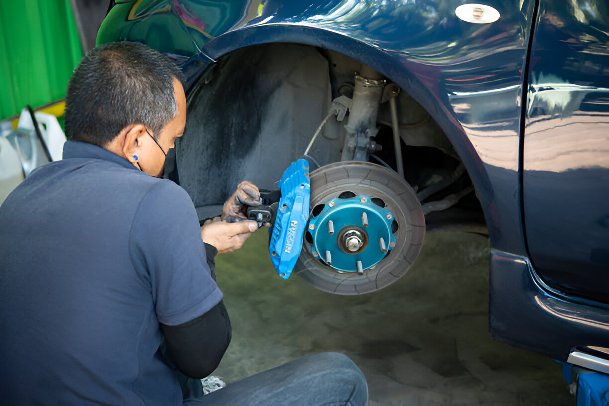 Mechanic working on car brake system with blue brake caliper
