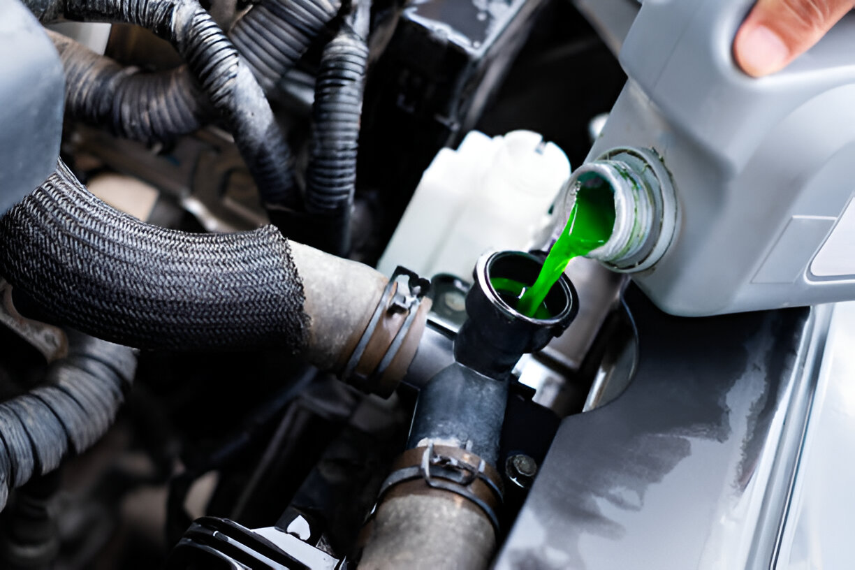 Bright green coolant being poured into car engine through funnel