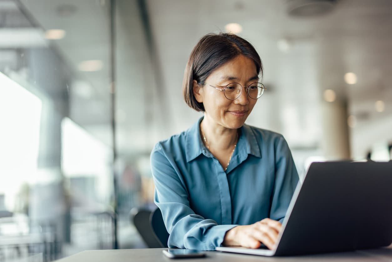 A woman smiling at her laptop.