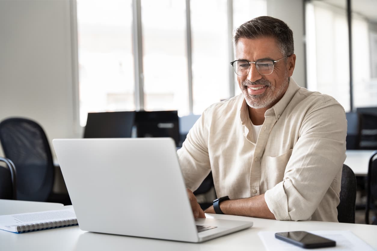 Man smiling at his laptop.