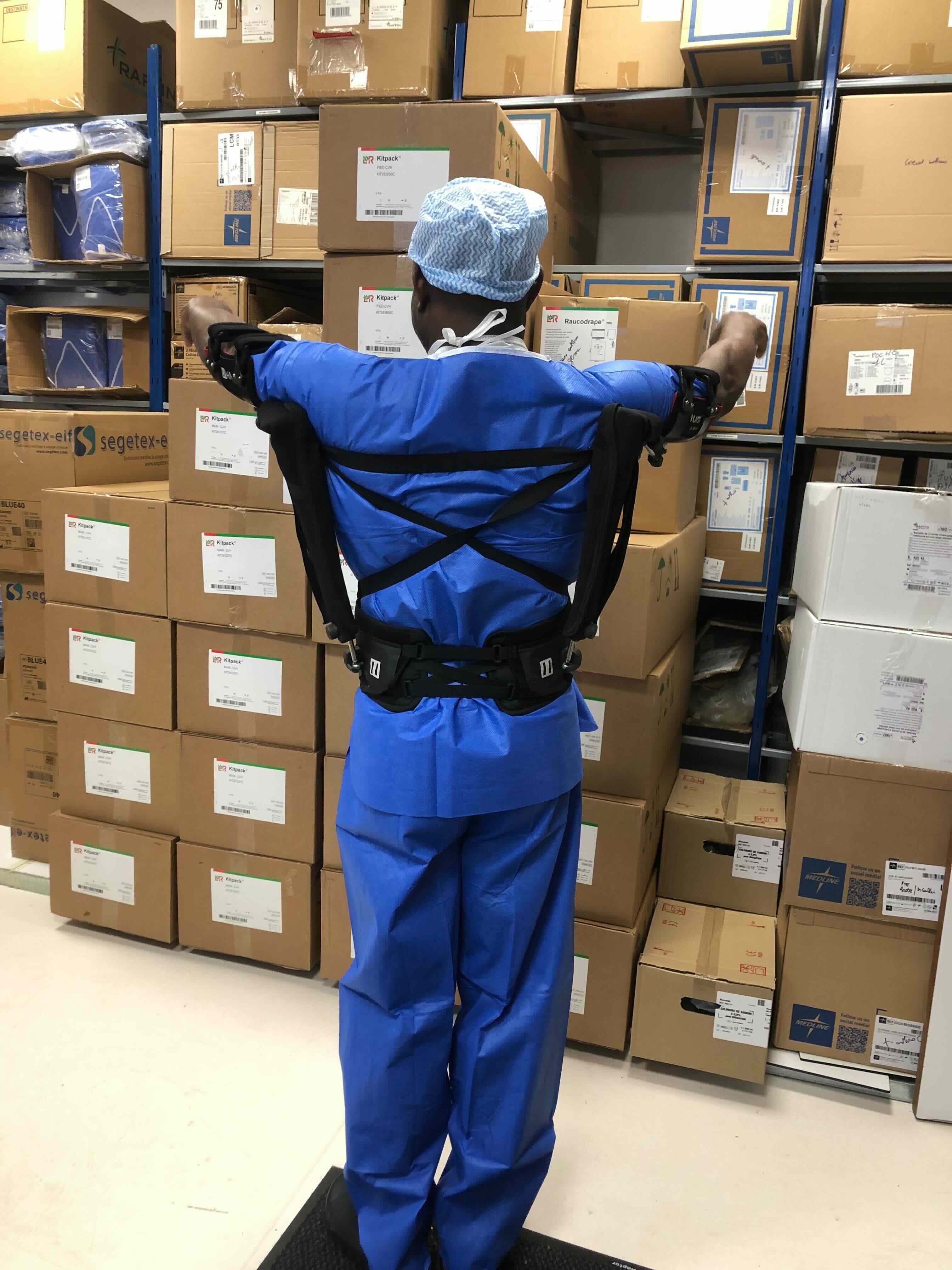 un préparateur en pharmacie d'hôpital porte un exosquelette pour les bras en l'air