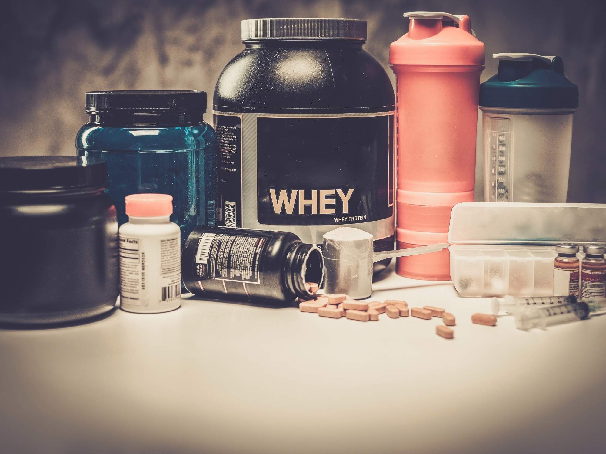 A group of assorted nutraceutical products like protein powder, vitamins, and workout drink containers