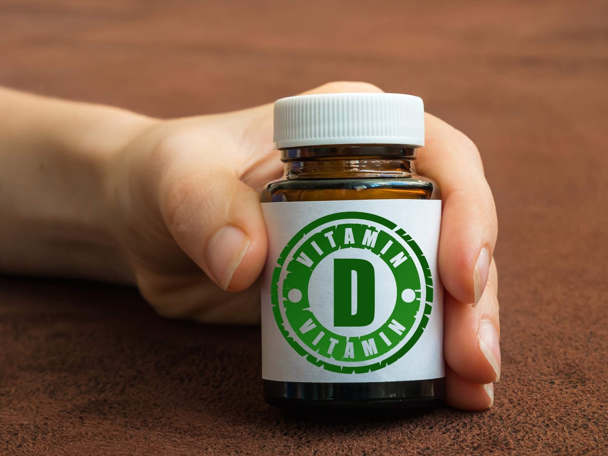 A hand holding a generic vitamin bottle.