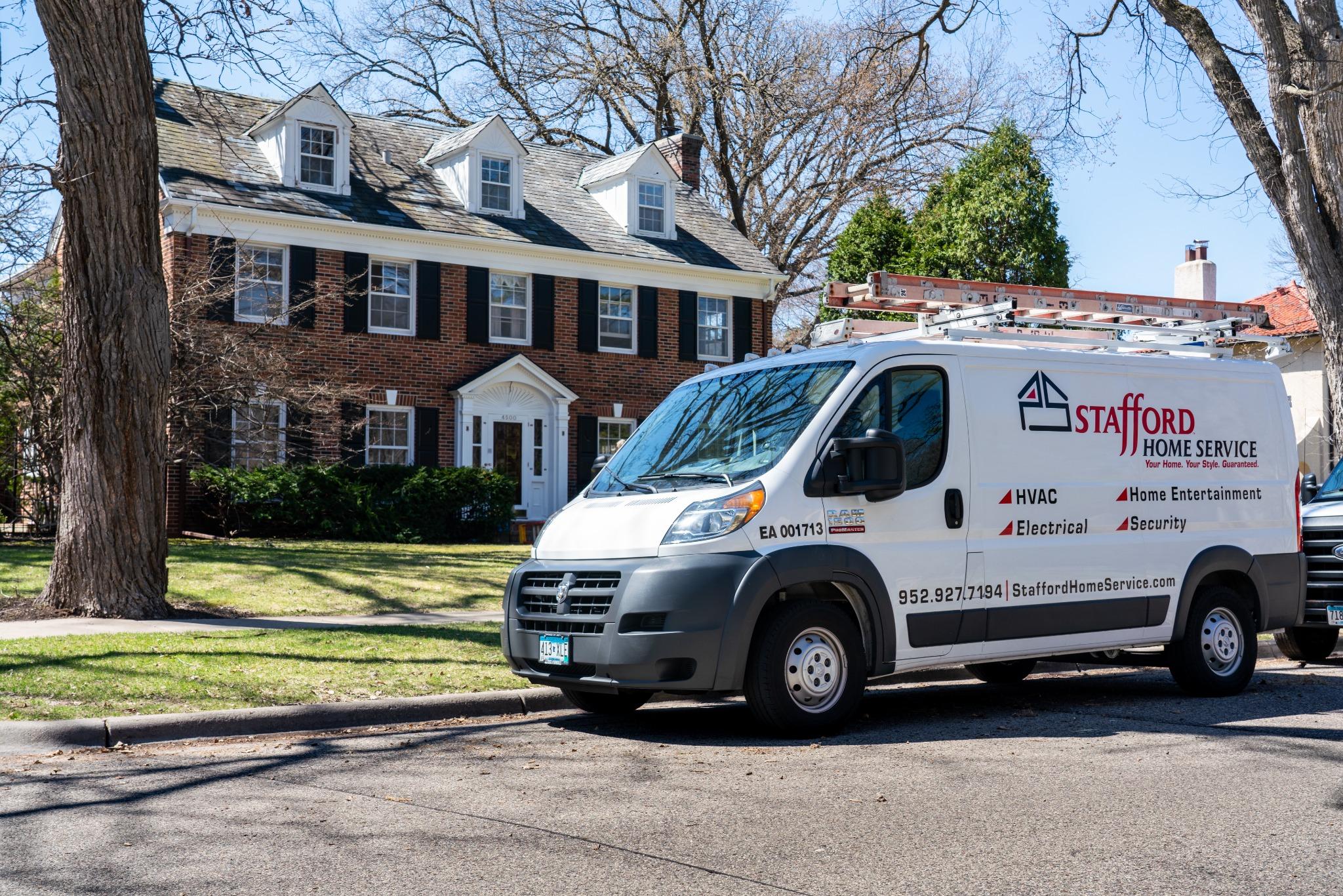 Stafford Home Service van parked in front of a classic brick house, ready for home improvement tasks.
